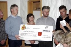 Das Bild zeigt Bürgermeister Martial Saddier und weitere Personen aus Bonneville, die einen Spendenscheck in Höhe von 13.000 Euro an Bürgermeiser Michael Benitz übergeben.