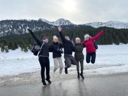 Jugendliche springen vor schneebedeckten Bergen vor Freude in die Luft